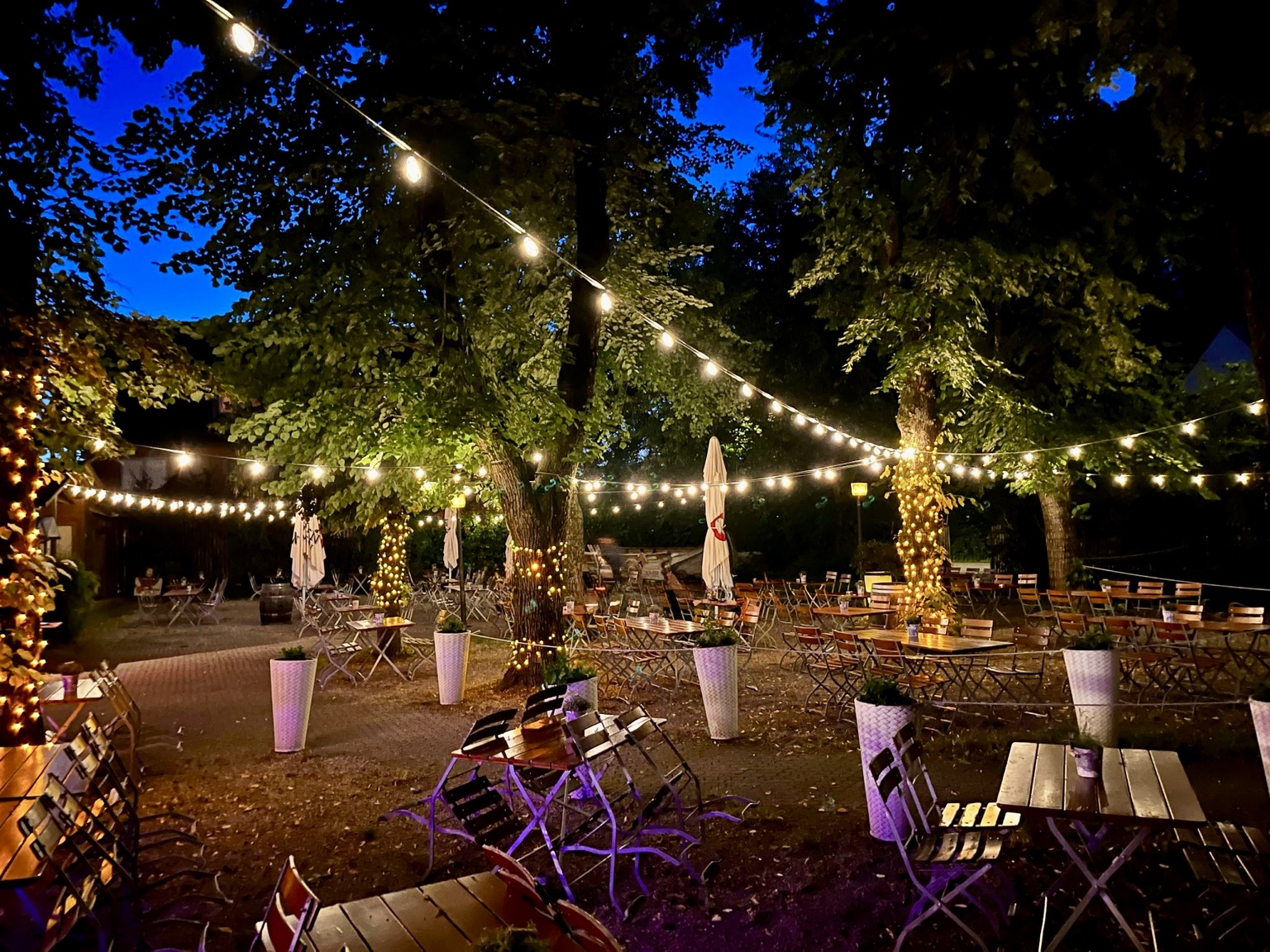 Biergarten am Abend unter Lichterketten